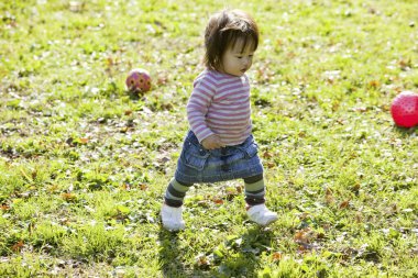 Küçük kız parkta toplarla oynuyor.