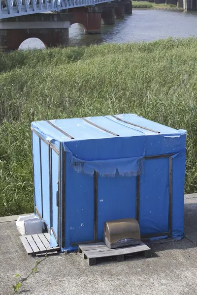 Mavi derme çatma sığınak çimenli nehir kıyısının yanında.