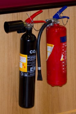 İki yangın söndürücü ahşap duvarda asılı.