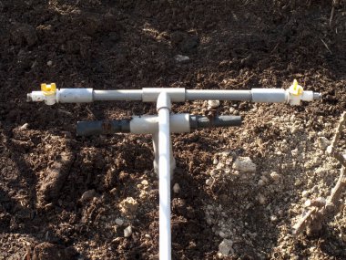 Metal sulama boru sistemi dışarıda kuru kahverengi toprak boyunca uzanır.