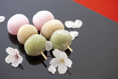 Lezzetli yuvarlak tatlılar çiçekler ve taç yapraklarıyla servis edilir. Japon Mochi. 