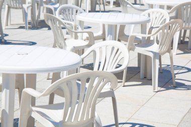 Güneşli bir günde boş beyaz sandalyeler ve masalar