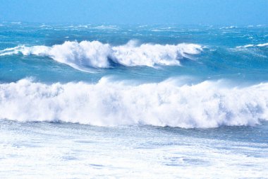 Denizdeki dalgaların gündüz görüntüsü. Denizin üzerindeki mavi gökyüzü