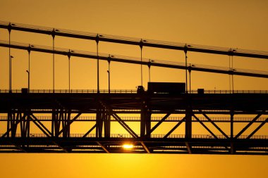 Arka planda dramatik günbatımı olan köprü silueti