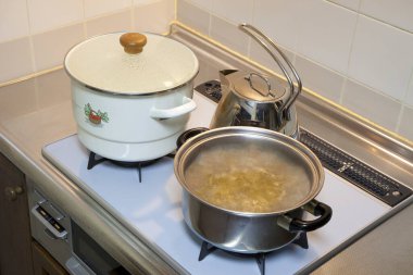 Tencere ve çaydanlık mutfak ocağında kaynıyor.