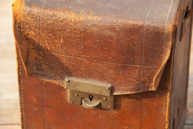 Weathered leather suitcase resting on wooden surface