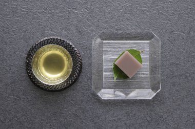 Çay fincanının en üst görüntüsü ve lezzetli Japon tatlıları masada.