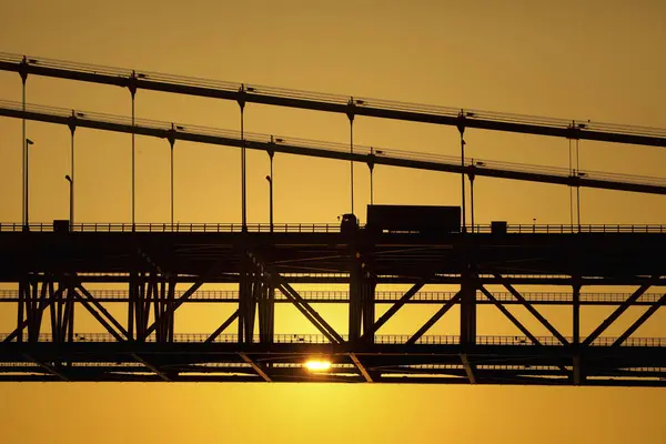 Arka planda dramatik günbatımı olan köprü silueti