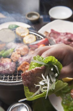 Japon restoranındaki ızgarada et ve sebze pişiren kişinin yakın çekim görüntüsü 