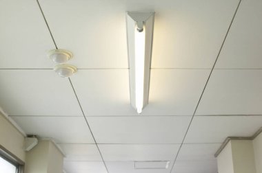 Beyaz tavan fayanslarını aydınlatan flüoresan lamba.