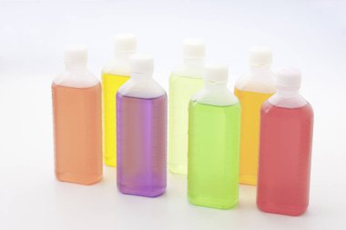 Işık arkaplanındaki renkli plastik sıvı şişelerinin yakın plan görüntüsü       