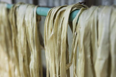 Uzun sarı erişteler pipoda sallanıyor.