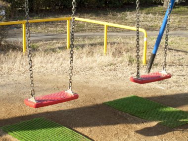 Oyun bahçesinde çimlerle boş salıncaklar