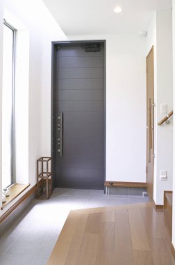 Karanlık kapılı, ahşap zemin pencereli modern minimalist giriş.