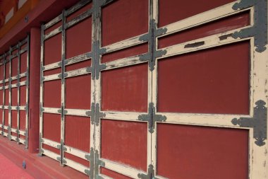 Süslü metal menteşeli kırmızı ahşap kapılar.