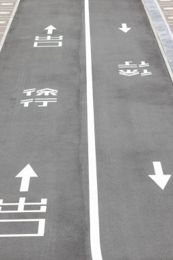 Beyaz yönlü ok ve sembollerin yer aldığı boş asfalt yol