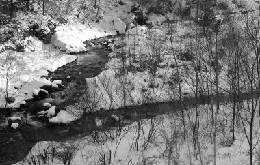 Dağ ormanındaki nehrin siyah beyaz görüntüsü. Kış manzarası
