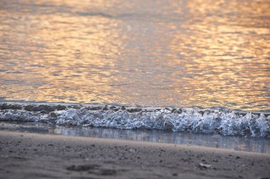 Gün batımında sahildeki deniz dalgalarının güzel manzarası.         
