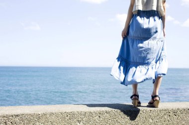 Deniz arka planında mavi gökyüzü olan kadın