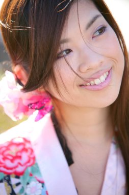 Saçında pembe çiçek olan Asyalı kadının portresini kapat.  