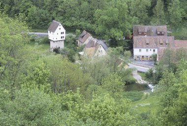 Küçük kır evleri yemyeşil ağaçlar ve çalılarla çevrili.