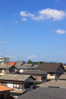 Berrak mavi gökyüzünün altında bulutlu çatıların görüntüsü