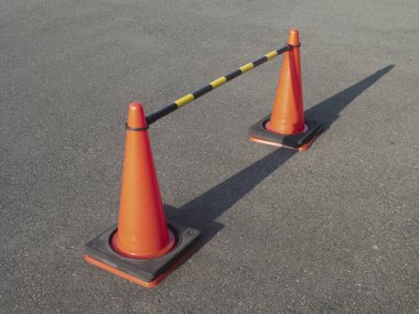 Açık havada çizgili plastik bariyerle birbirine bağlı iki turuncu trafik konisi
