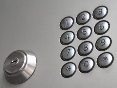 Gümüş kapı kilidinin yanında yuvarlak düğmeler içeren metal tuş takımı