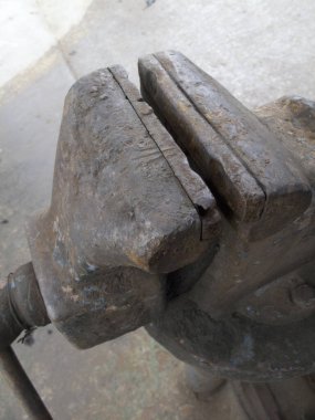 Beton yüzeyde duran paslı metal mengene