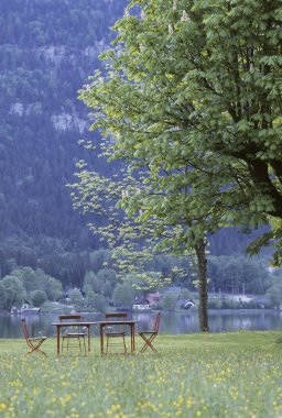 Dağlarda gölde sandalyeli masa manzarası