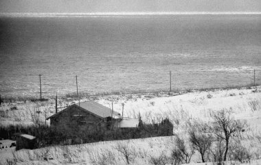 Deniz kıyısındaki ahşap bir evin siyah beyaz fotoğrafı. 