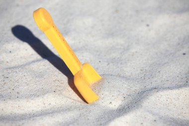 Kumsalda sarı plastik kürek.
