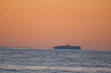 Gün batımında deniz üzerinde turuncu gökyüzü manzarası 