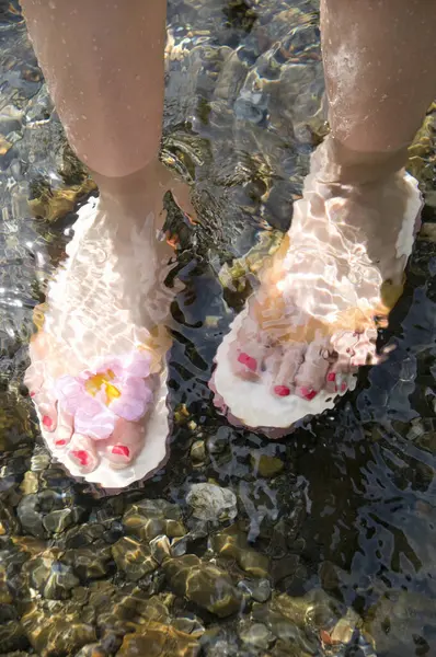 Female Feet Wearing Flip-Flops In The Water