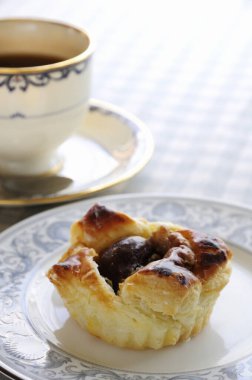 Zarif porselen kahve fincanının yanında duran yumuşak pasta turtası.