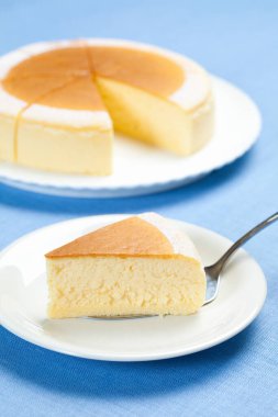 Beyaz arka planda beyaz tabakta peynirli kek.