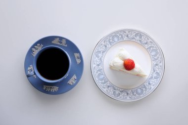 Kremalı çilekli kek ve bir fincan çay.