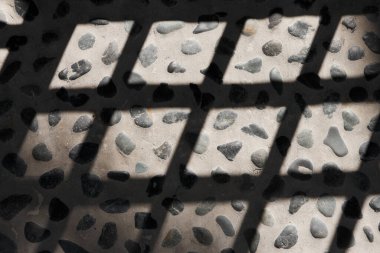 Taş kaldırımdaki kafes kapısının gölgesi