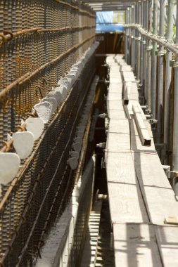 Dışarıdaki metal iskeleler arasında dar inşaat geçidi var.