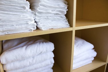 Tahta raflarda temiz beyaz havlular var.           