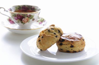 Beyaz arkaplanda çay olan çikolata parçacıklı kurabiyeler.