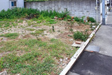 Beton duvar ve kaldırım kenarındaki boş arazi.