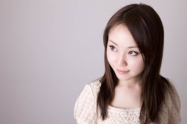 Genç ve güzel Asyalı bir kadının açık arkaplandaki yakın çekimi.