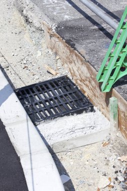 Siyah metal rögar ızgarası beton kaldırımın yanına kurulmuş.