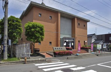 Geniş pencereli ve çevresindeki yeşilliklere sahip modern tuğla bina