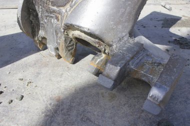 Metal makine parçası dışarıda beton yüzeyde duruyor.