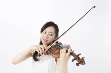 Beyaz arka planda keman çalan Asyalı kadın. 
