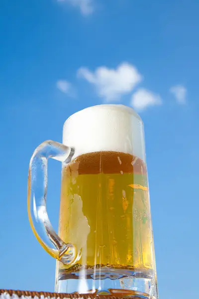 美しい青い空と白い雲の背景にビールのグラス — ストック写真