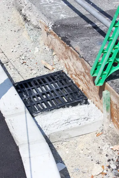 Siyah metal rögar ızgarası beton kaldırımın yanına kurulmuş.