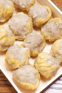 Ahşap tepsinin içine yerleştirilmiş domuz buğulaması.